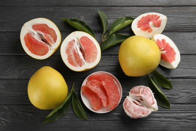 Photo of Fresh cut and whole pomelo fruits on grey wooden table, flat lay