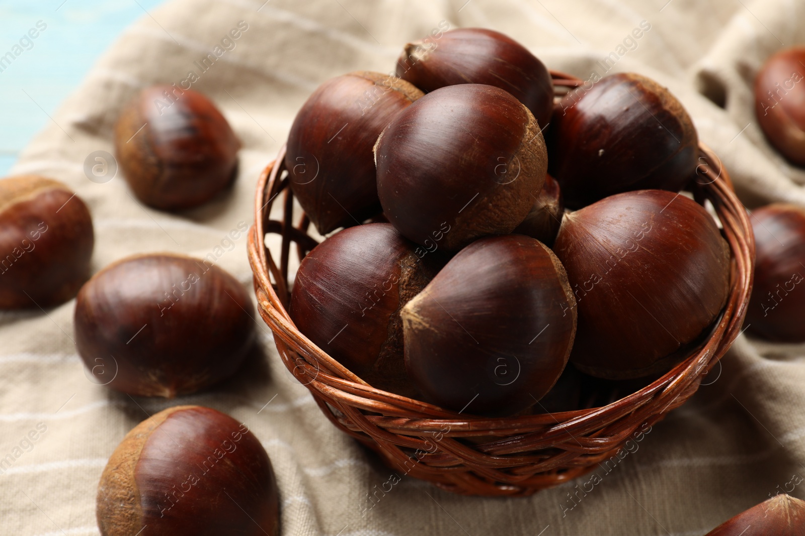 Photo of Wicker bowl with roasted edible sweet chestnuts on table, closeup