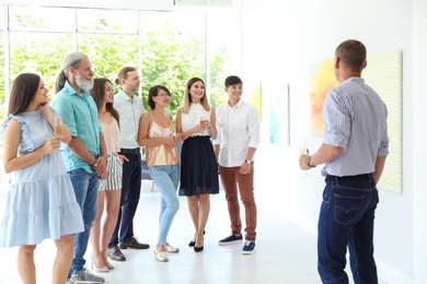 Group of people with guide at exhibition in art gallery