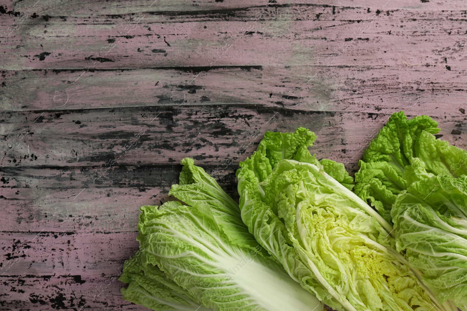 Photo of Cut fresh ripe Chinese cabbages on rustic table, flat lay. Space for text