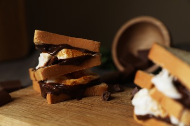 Photo of Delicious marshmallow sandwiches with bread and chocolate on wooden board, closeup