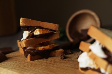 Delicious marshmallow sandwiches with bread and chocolate on wooden board, closeup