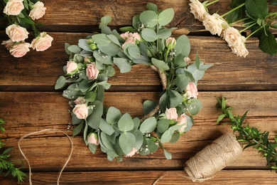 Photo of Flat lay composition with wreath made of beautiful flowers on wooden table