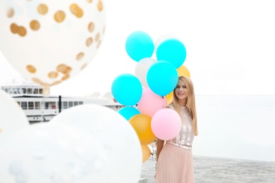 Photo of Beautiful young woman with bunch of balloons outdoors