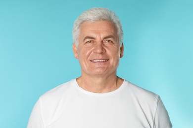 Photo of Mature man with healthy teeth on color background