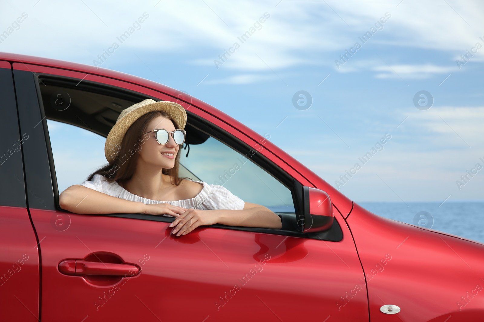 Photo of Happy woman leaning out of car window on beach. Summer vacation trip