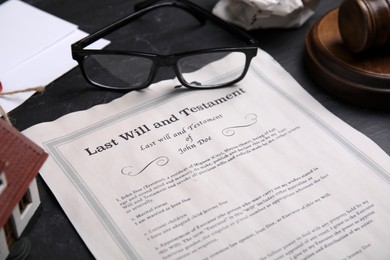 Photo of Last will and testament near glasses on black table, closeup