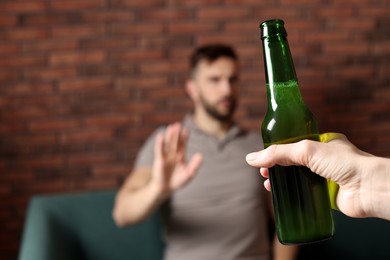 Man refusing to drink beer indoors, closeup. Alcohol addiction treatment