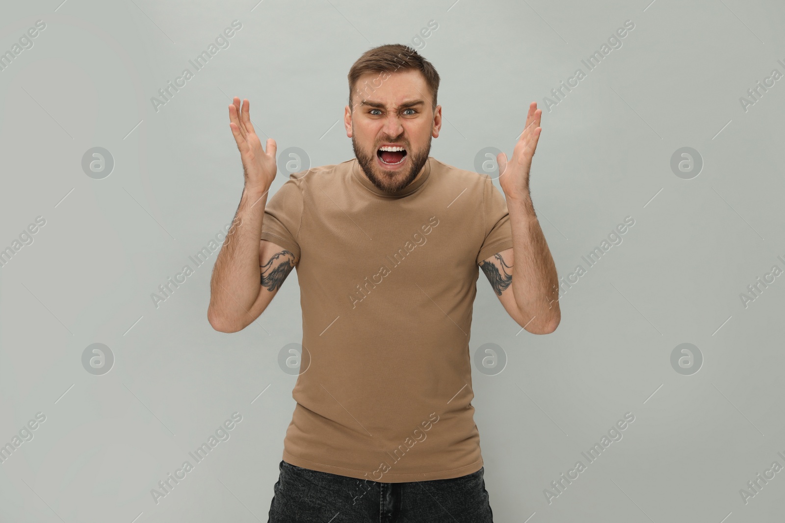 Photo of Angry young man on grey background. Hate concept