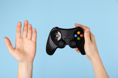 Photo of Woman with game controller on light blue background, closeup