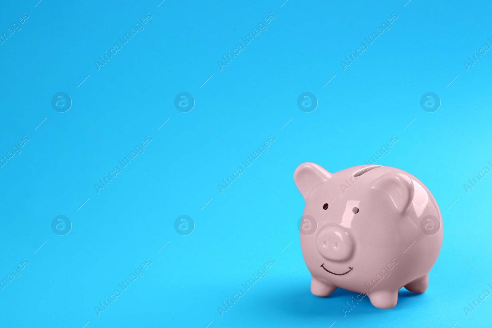 Photo of Pink piggy bank on blue background. Space for text