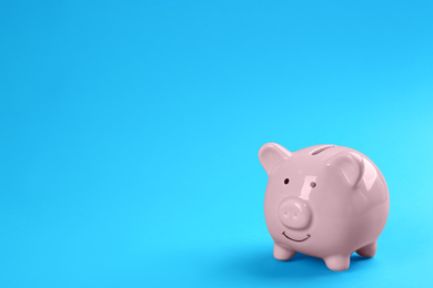 Photo of Pink piggy bank on blue background. Space for text