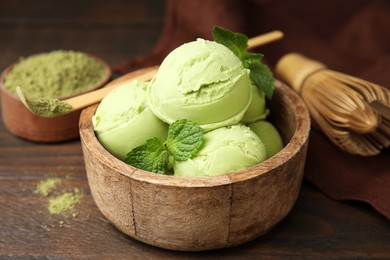 Photo of Tasty matcha ice cream in bowl and bamboo spoon with powder on wooden table, closeup