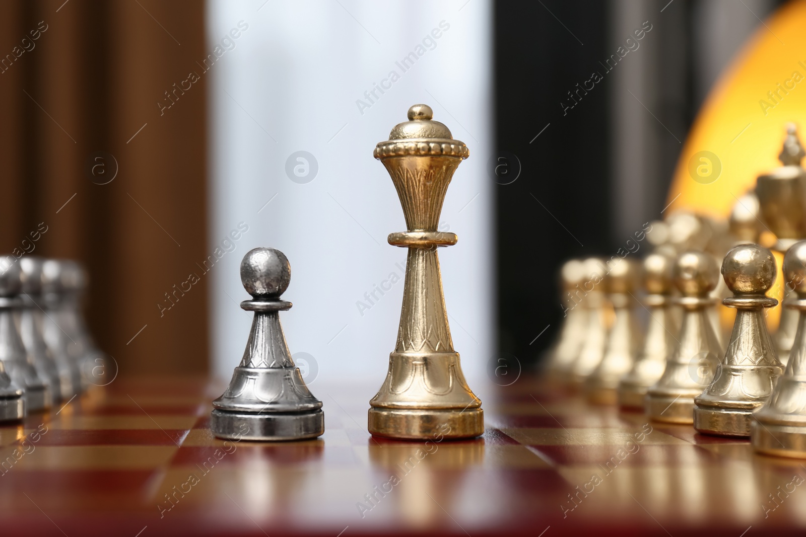 Photo of Queen and pawn piece among others on chessboard indoors