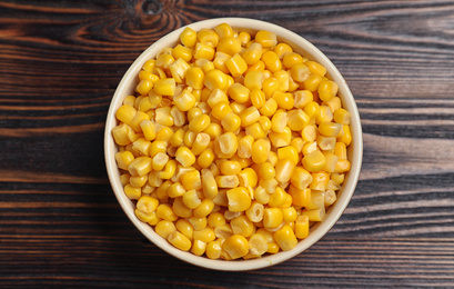 Delicious canned corn in bowl on wooden table, top view