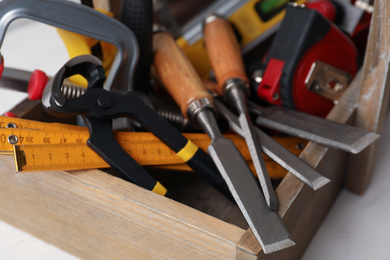 Photo of Different carpenter's tools in wooden box on table, closeup