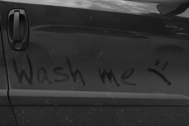 Inscription WASH ME and sad smiley on dirty car, closeup