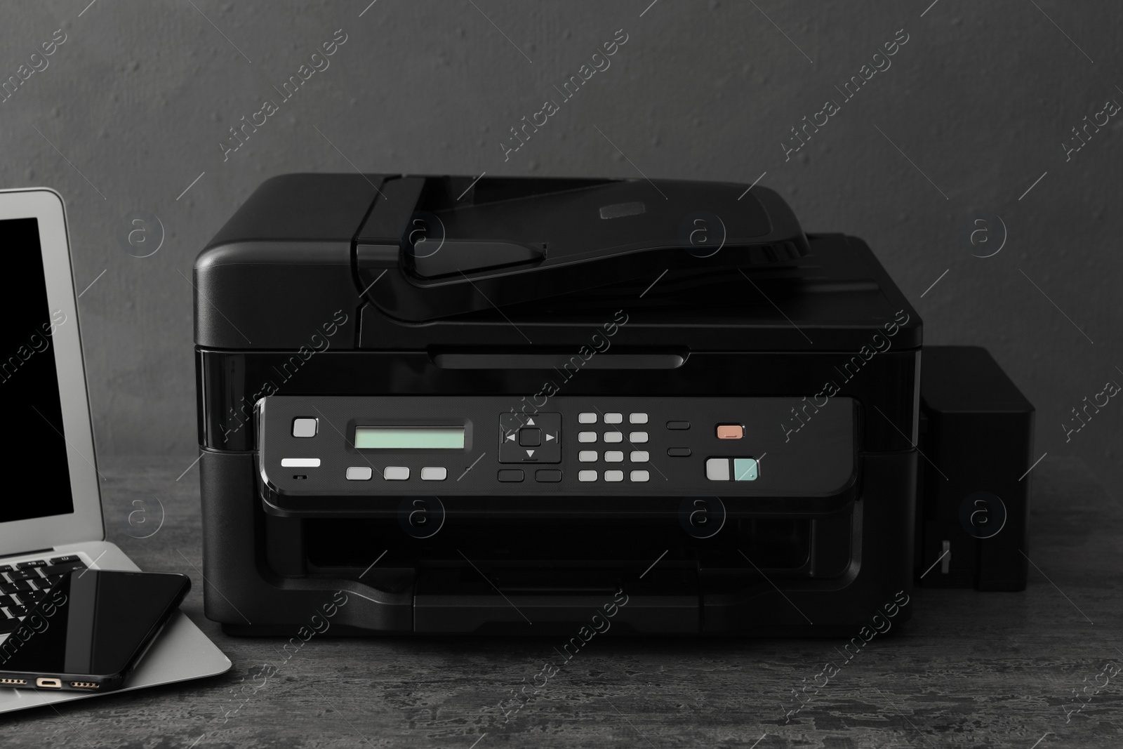 Photo of New modern printer and smartphone on grey table