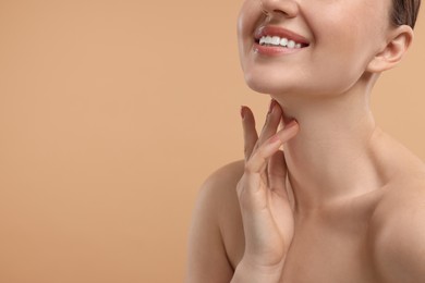 Photo of Smiling woman touching her neck on beige background, closeup. Space for text