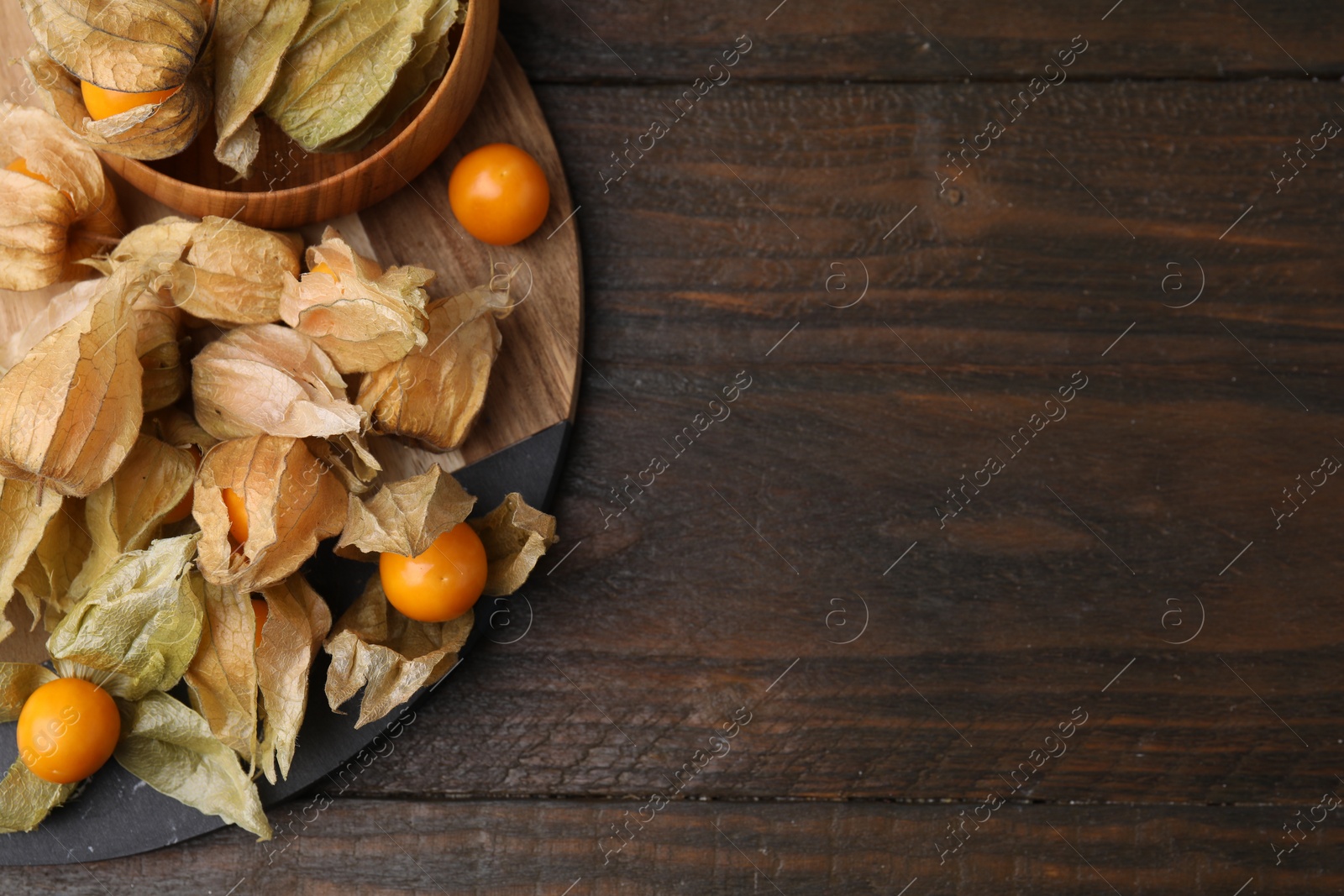 Photo of Ripe physalis fruits with calyxes on wooden table, top view. Space for text