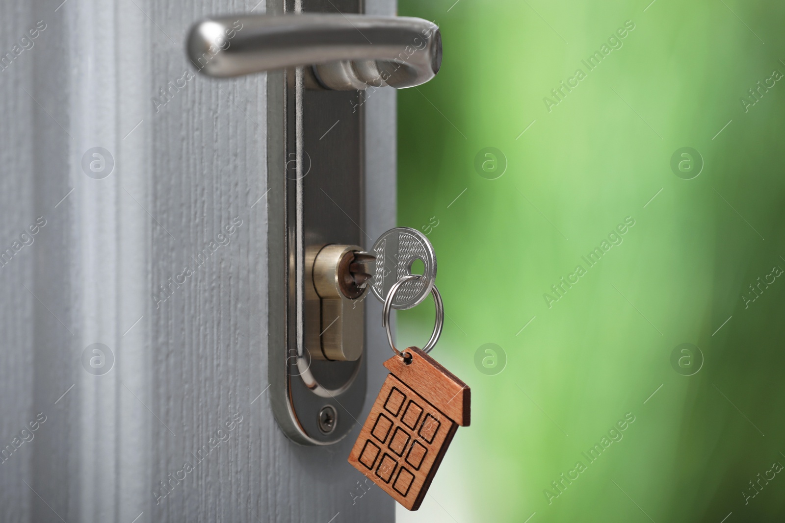 Photo of Open door with key on blurred background, closeup