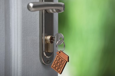 Open door with key on blurred background, closeup