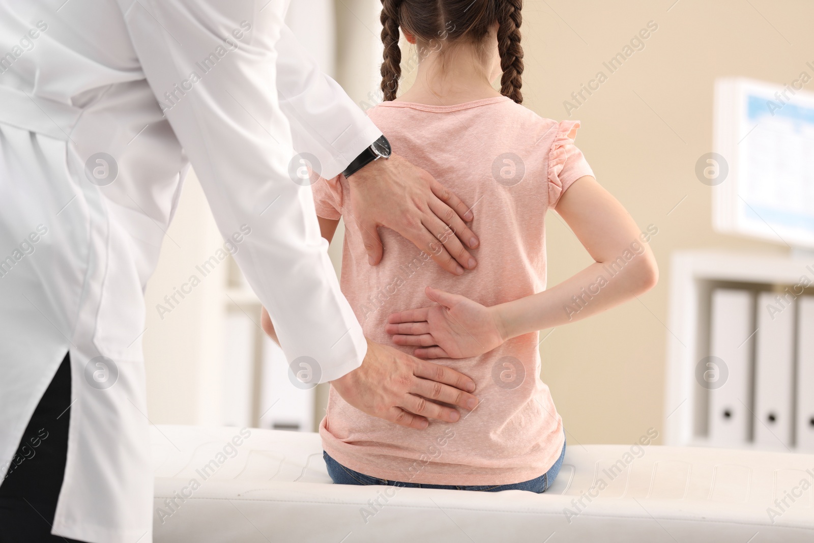 Photo of Chiropractor examining child with back pain in clinic, closeup