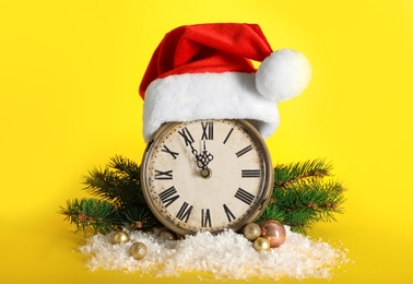 Photo of Vintage alarm clock with Christmas decor on yellow background. New Year countdown