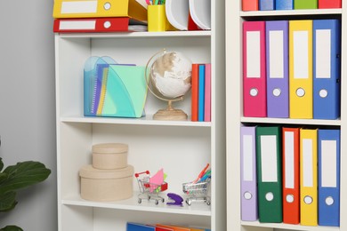 Photo of Colorful binder office folders and other stationery on shelving unit indoors