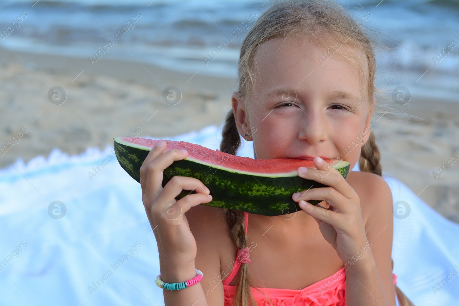 Photo of Cute little girl eating juicy watermelon on beach