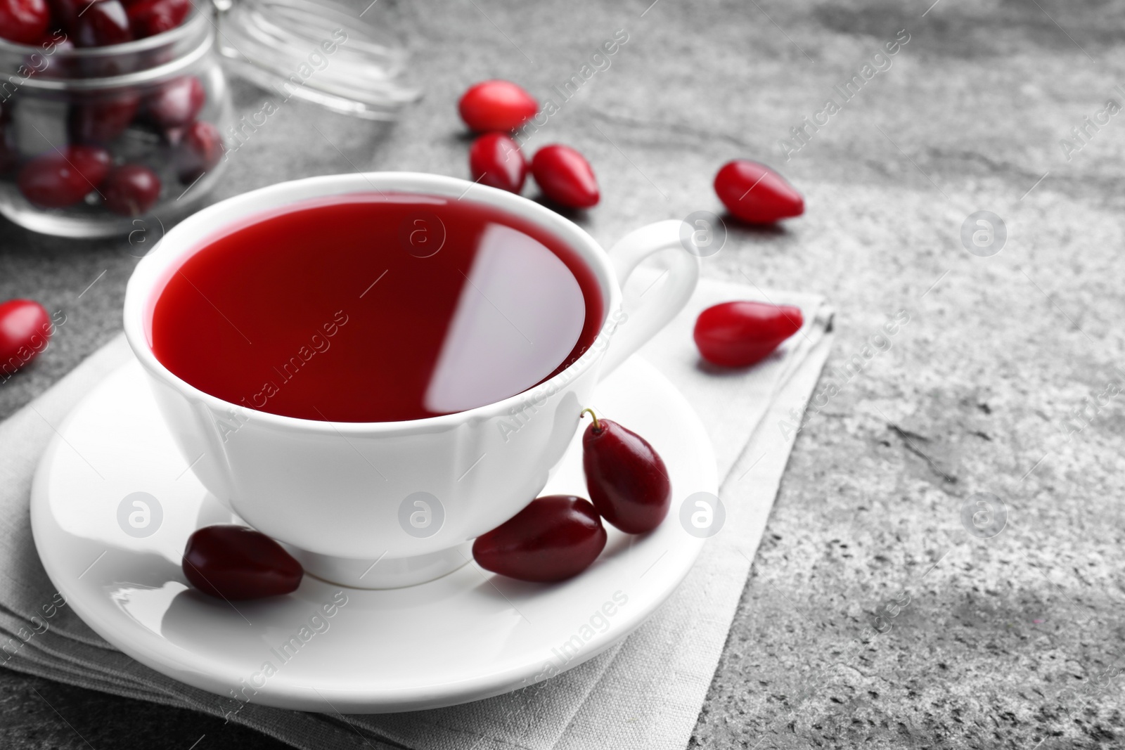 Photo of Cup of fresh dogwood tea and berries on grey table. Space for text