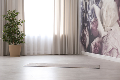 Grey yoga mat on floor in spacious room