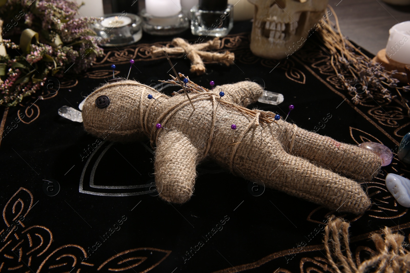 Photo of Voodoo doll with pins and dried flowers on table