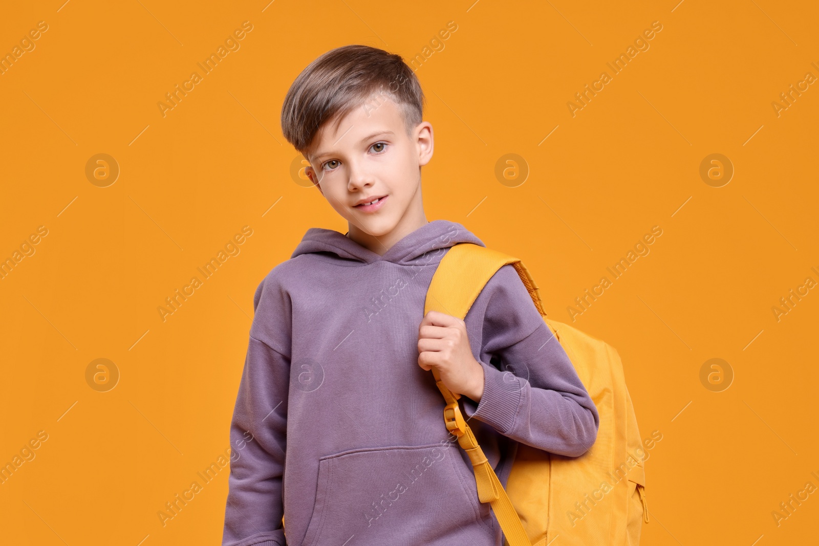 Photo of Back to school. Cute boy with backpack on orange background