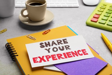 Photo of Share Your Experience. Workplace with card and stationery on light table