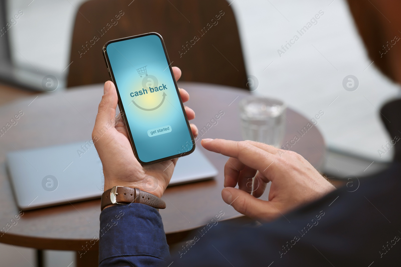 Image of Man using smartphone with word Cashback and shopping cart icon indoors, closeup