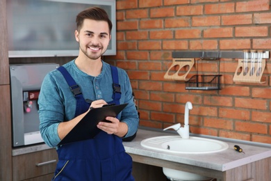 Photo of Male plumber with clipboard in kitchen. Repair service