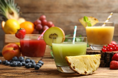 Delicious colorful juices in glasses and fresh ingredients on wooden table