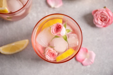 Tasty refreshing lemon drink with roses on light grey table, top view