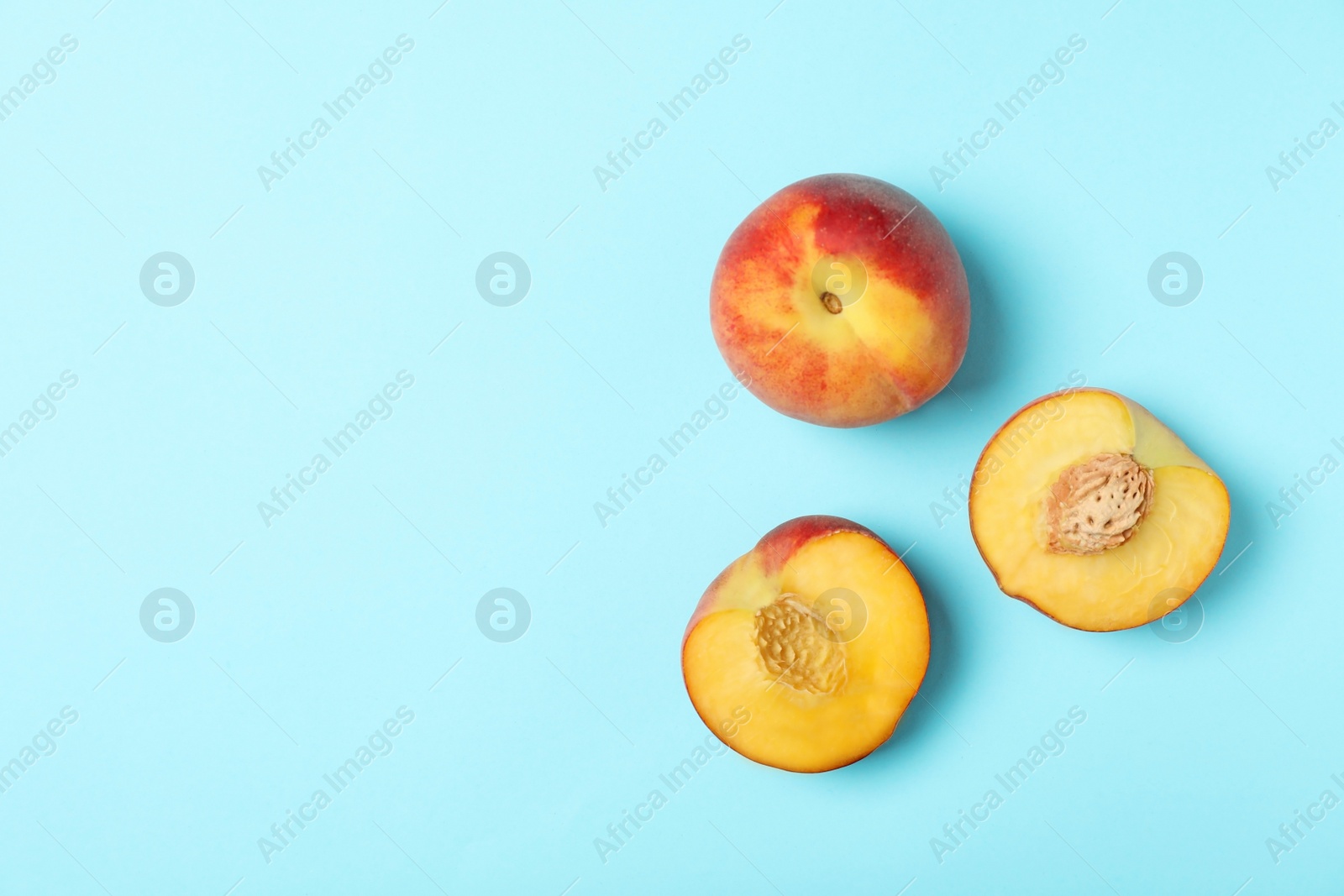 Photo of Sweet juicy peaches on light blue background, top view. Space for text