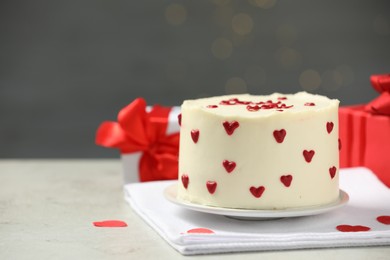 Bento cake with red cream hearts and gift boxes on grey table, space for text. St. Valentine's day surprise