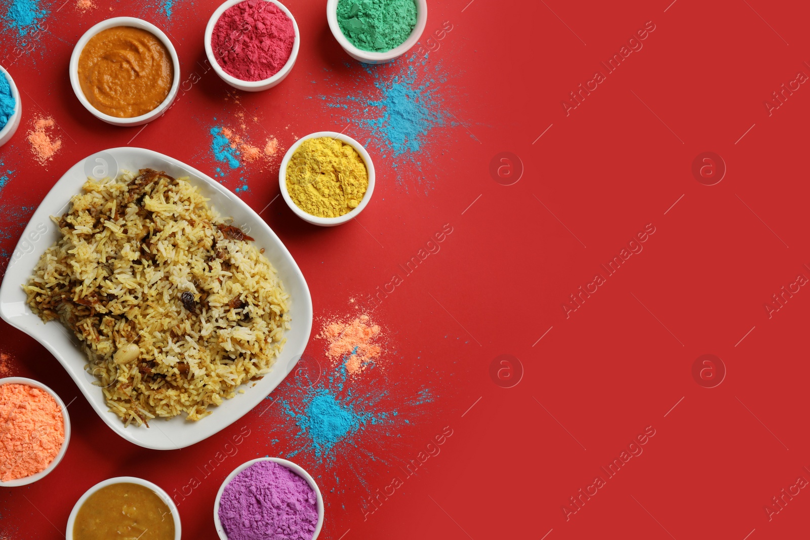Photo of Flat lay of traditional Indian food and color powder dyes on red background, space for text. Holi festival