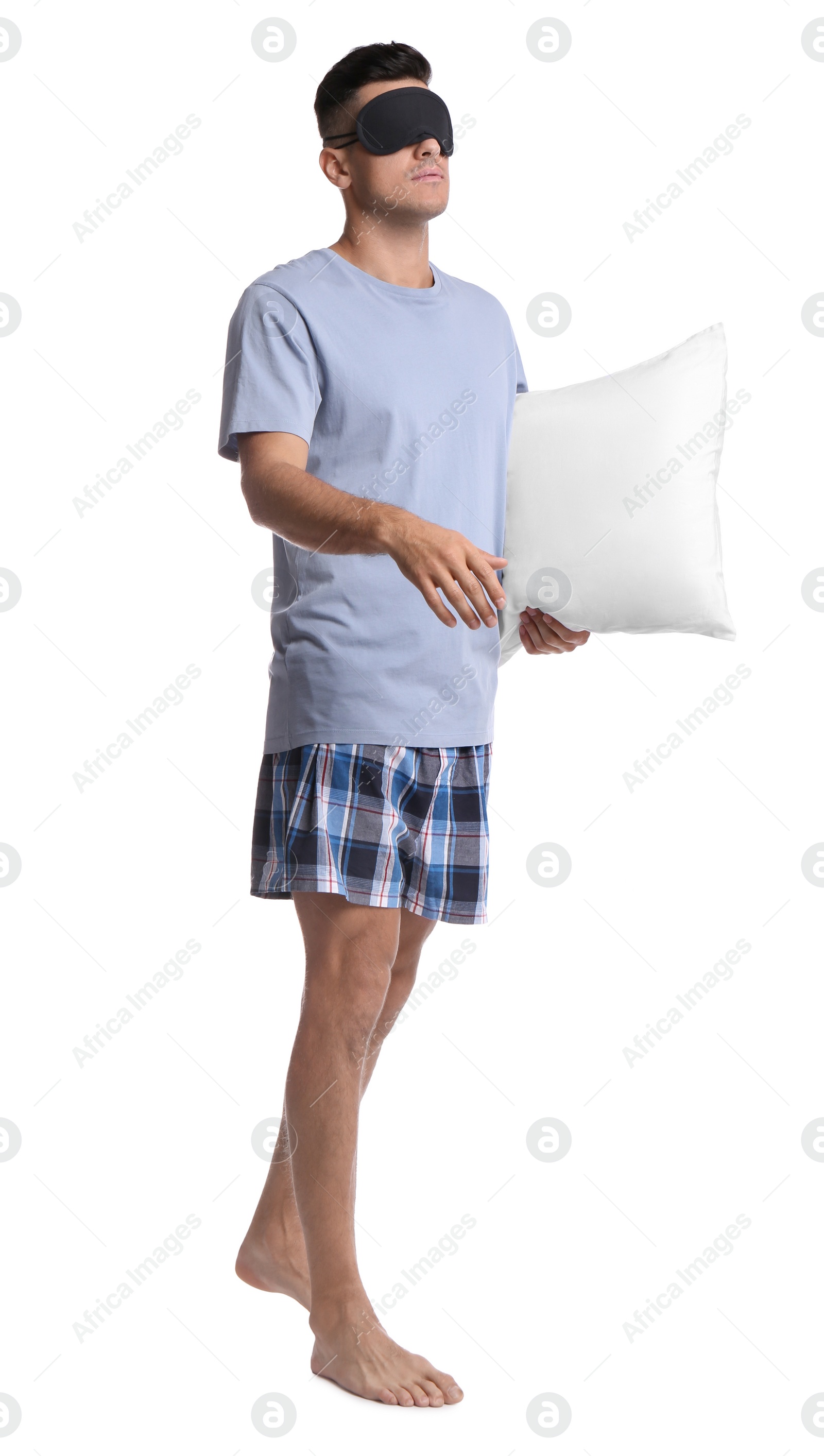 Photo of Somnambulist with blindfold and soft pillow on white background. Sleepwalking