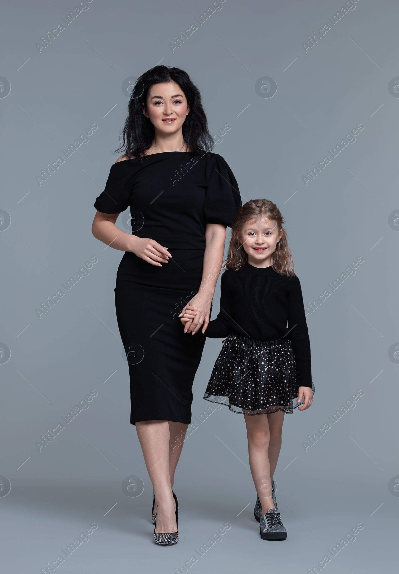 Photo of Beautiful mother with little daughter on grey background