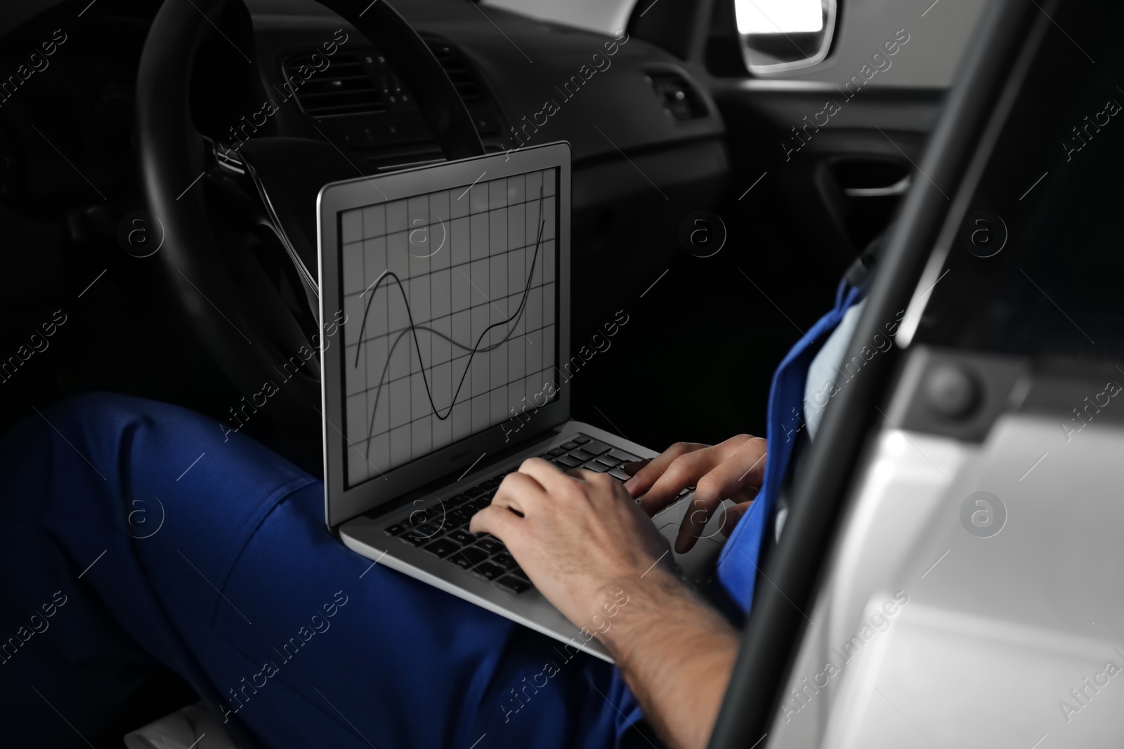 Photo of Mechanic with laptop doing car diagnostic at automobile repair shop, closeup