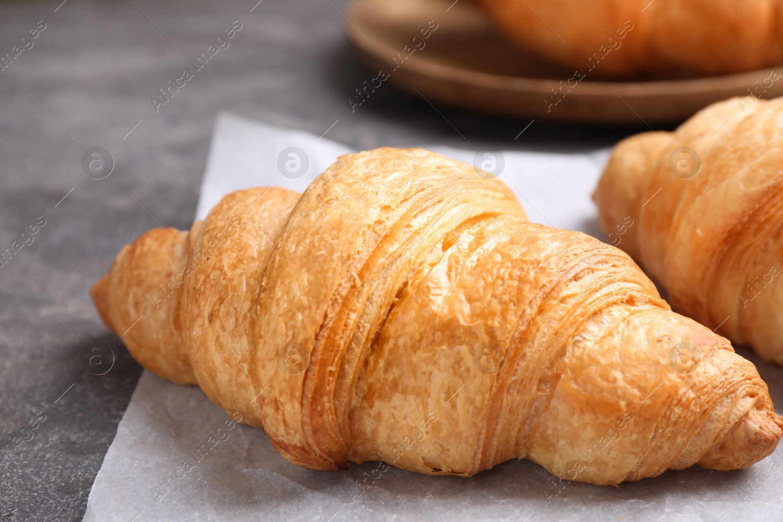 Photo of Tasty fresh croissants on grey table, closeup