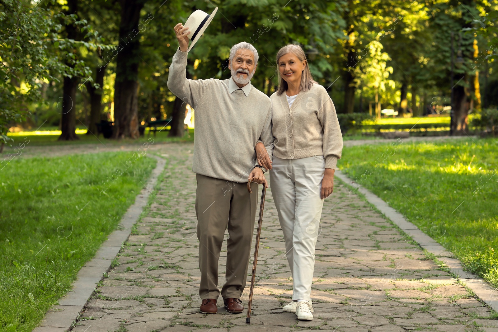 Photo of Senior man with walking cane and mature woman in park