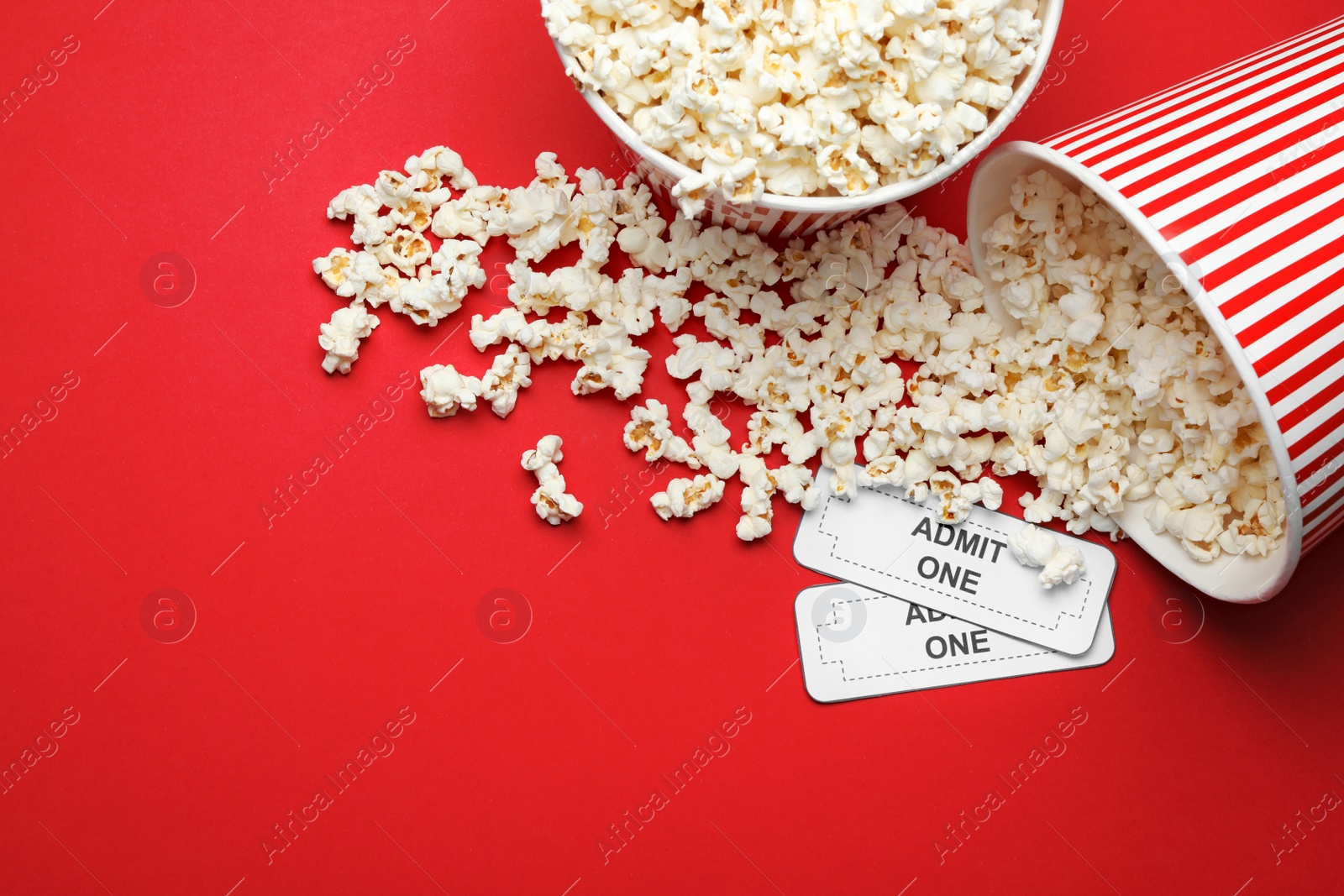 Photo of Popcorn and tickets on red background, flat lay. Cinema snack