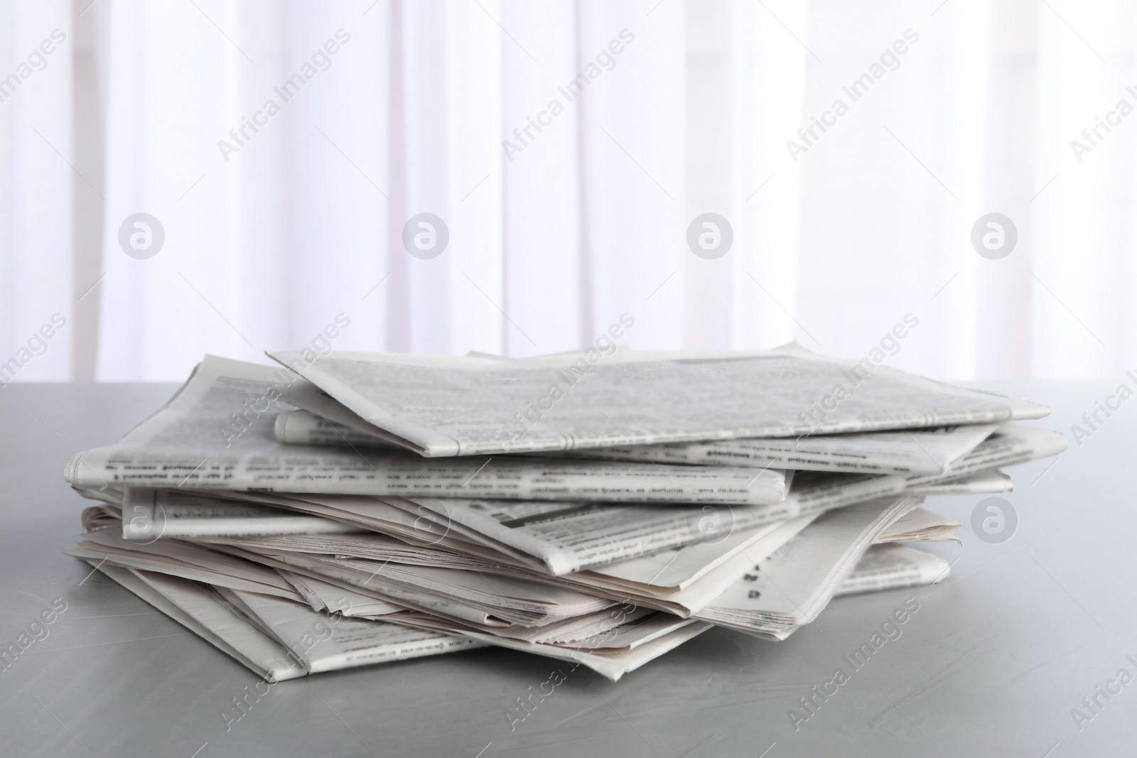 Photo of Pile of newspapers on grey table. Journalist's work