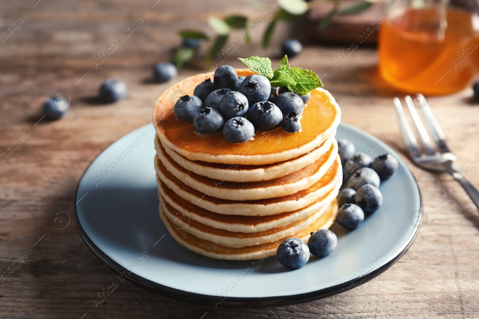Photo of Plate with pancakes and berries on wooden table